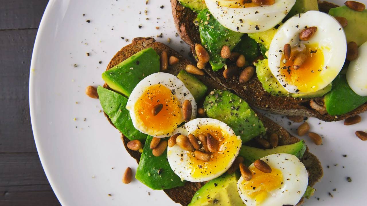 Plate of healthy food of soft boiled eggs, avacado, seeds and toast.