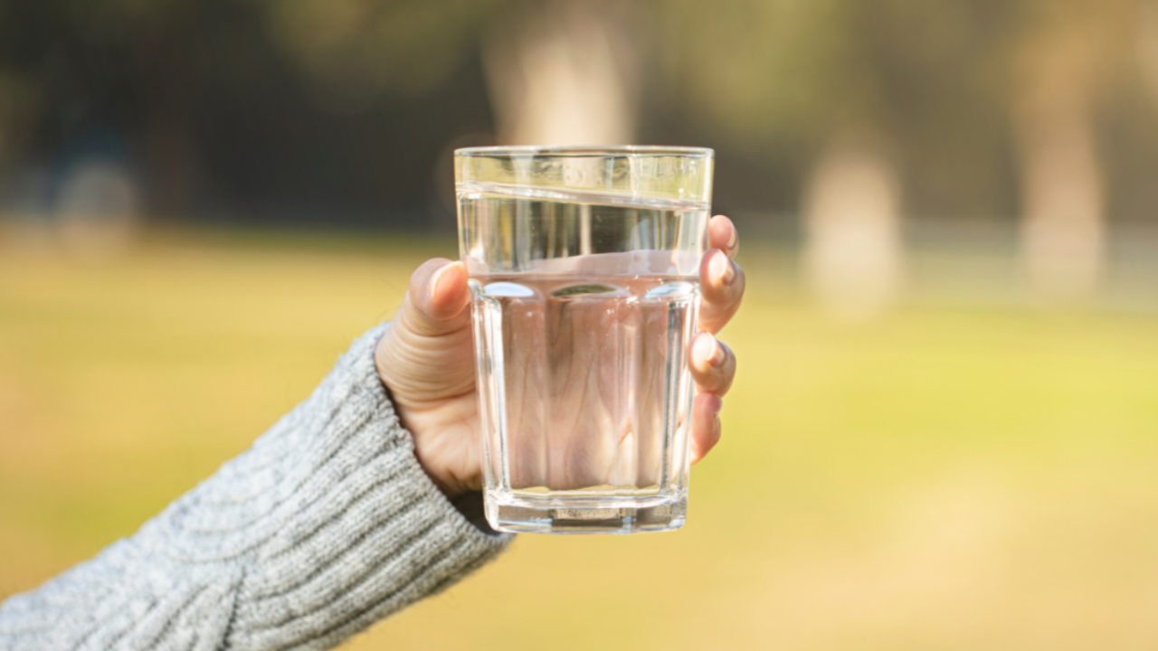 Woman holding a glass of water illustrating how stress feels heavier the longer you hold it