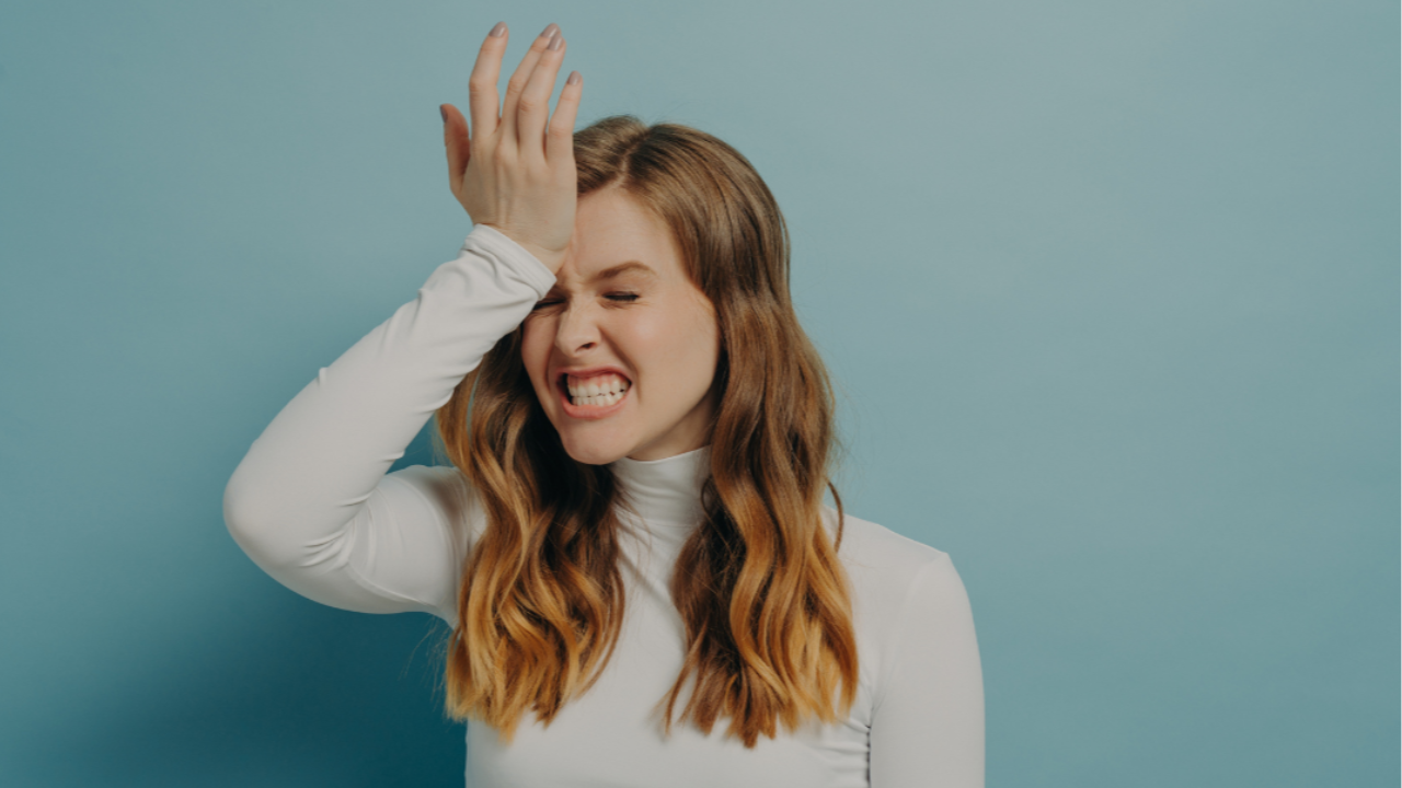 Woman with the palm of her hand on her head, looking anguished