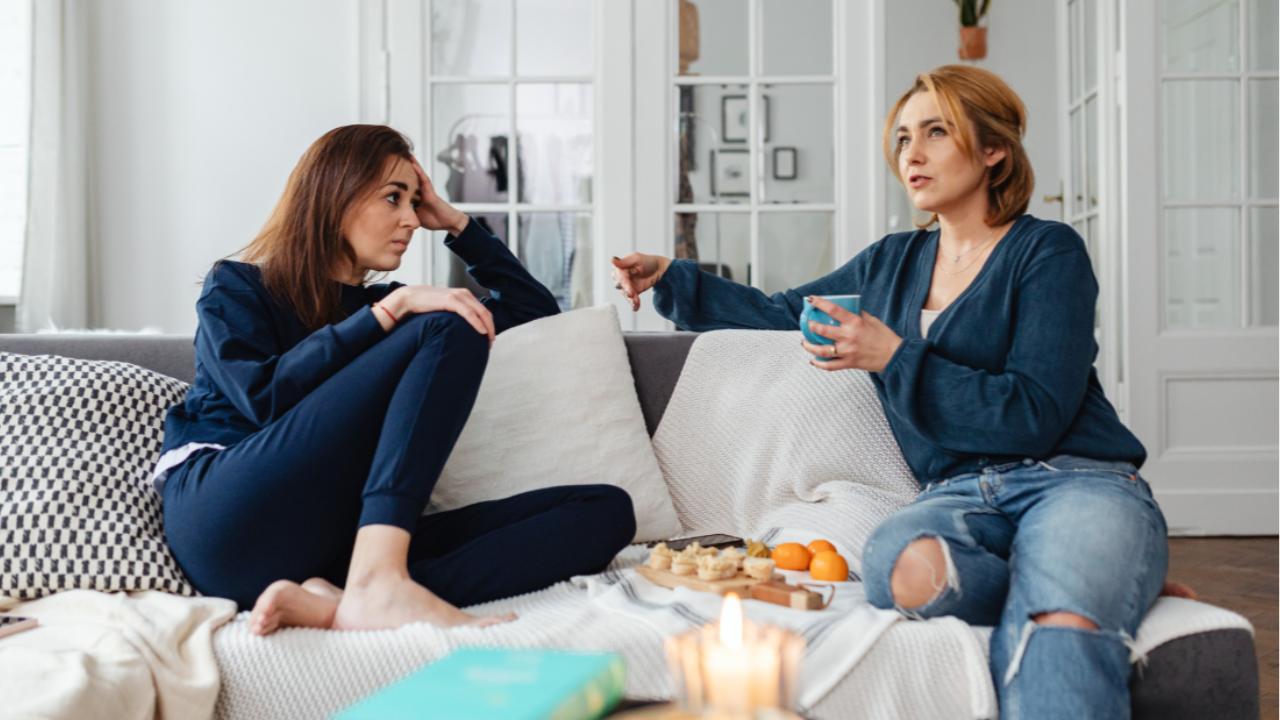 Two women sitting on a sofa, having a heartfelt conversation and sharing support