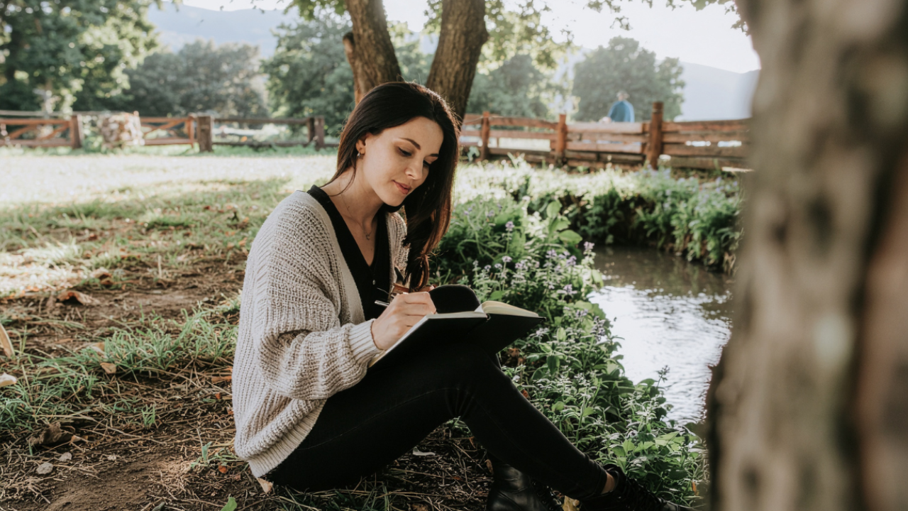 Woman journaling outdoors in a quiet, peaceful setting