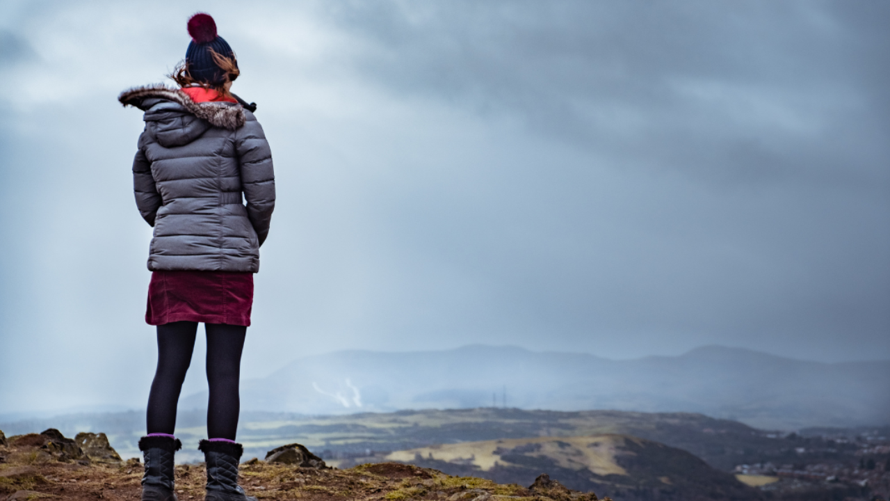 Woman looking out over mountains, reflecting and embracing the view