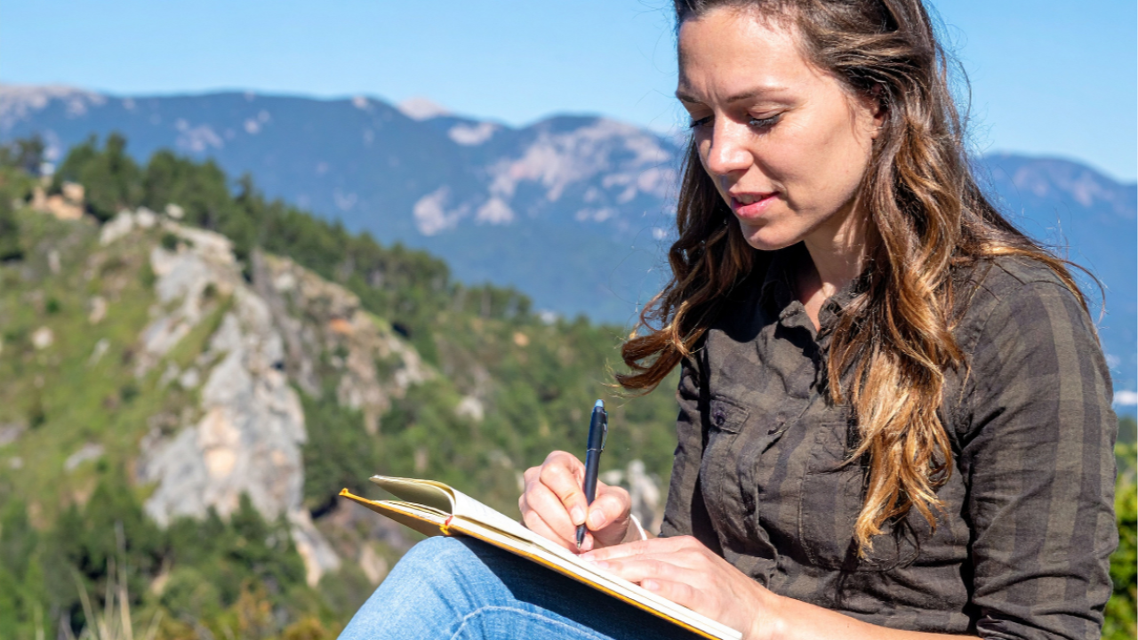 Woman Writing in Journal in the Mountains