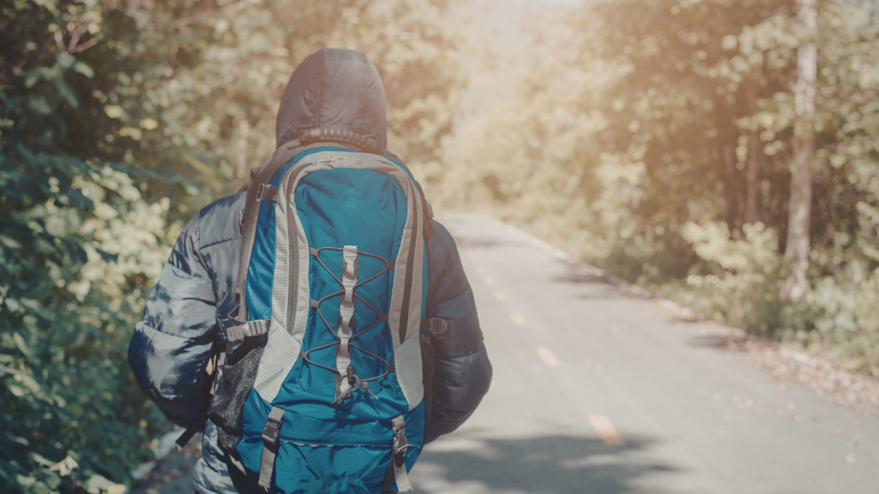 Person walking down a long road with a backpack, symbolising personal growth, self-discovery, and taking steps into the unknown