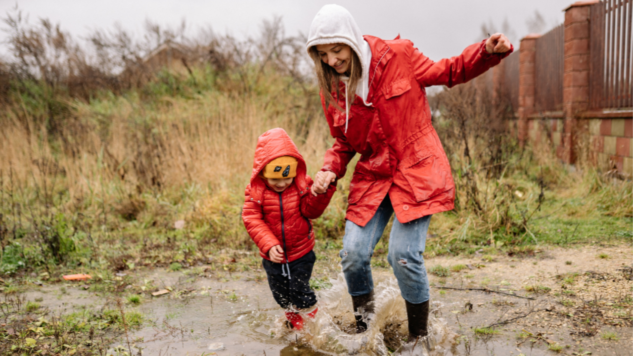A mother and son playing in puddles together, enjoying the moment and connecting