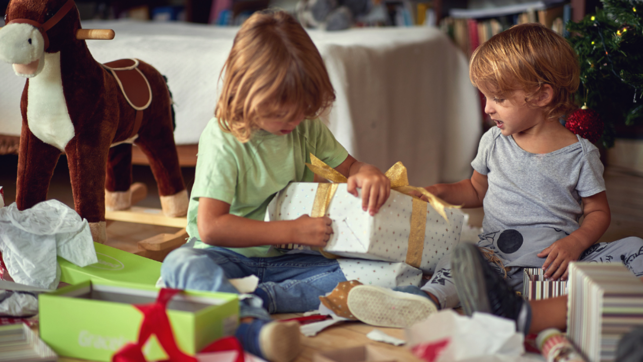 Children unwrapping Christmas presents near a decorated tree