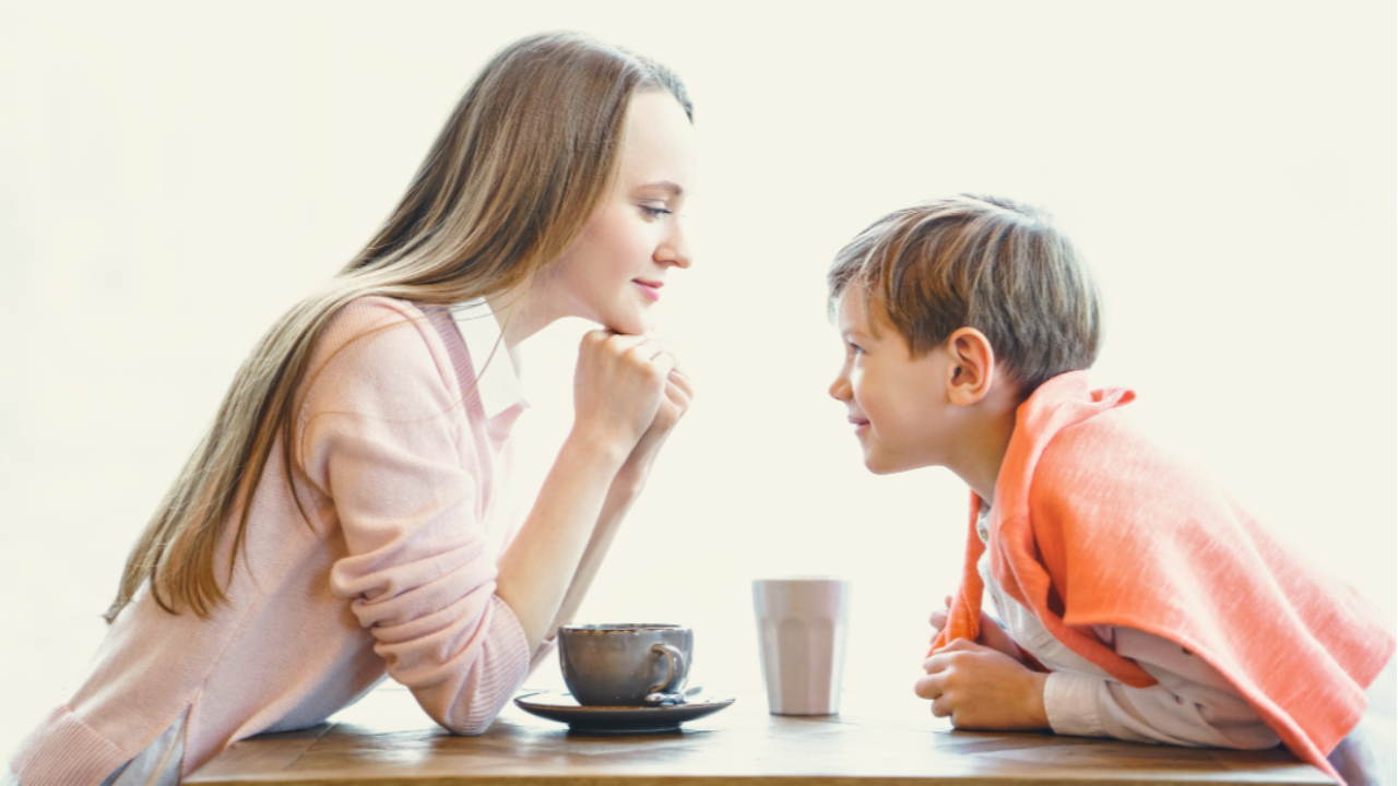 A woman and a young boy sitting across from each other at a table, enjoying their drinks and each otherās company.