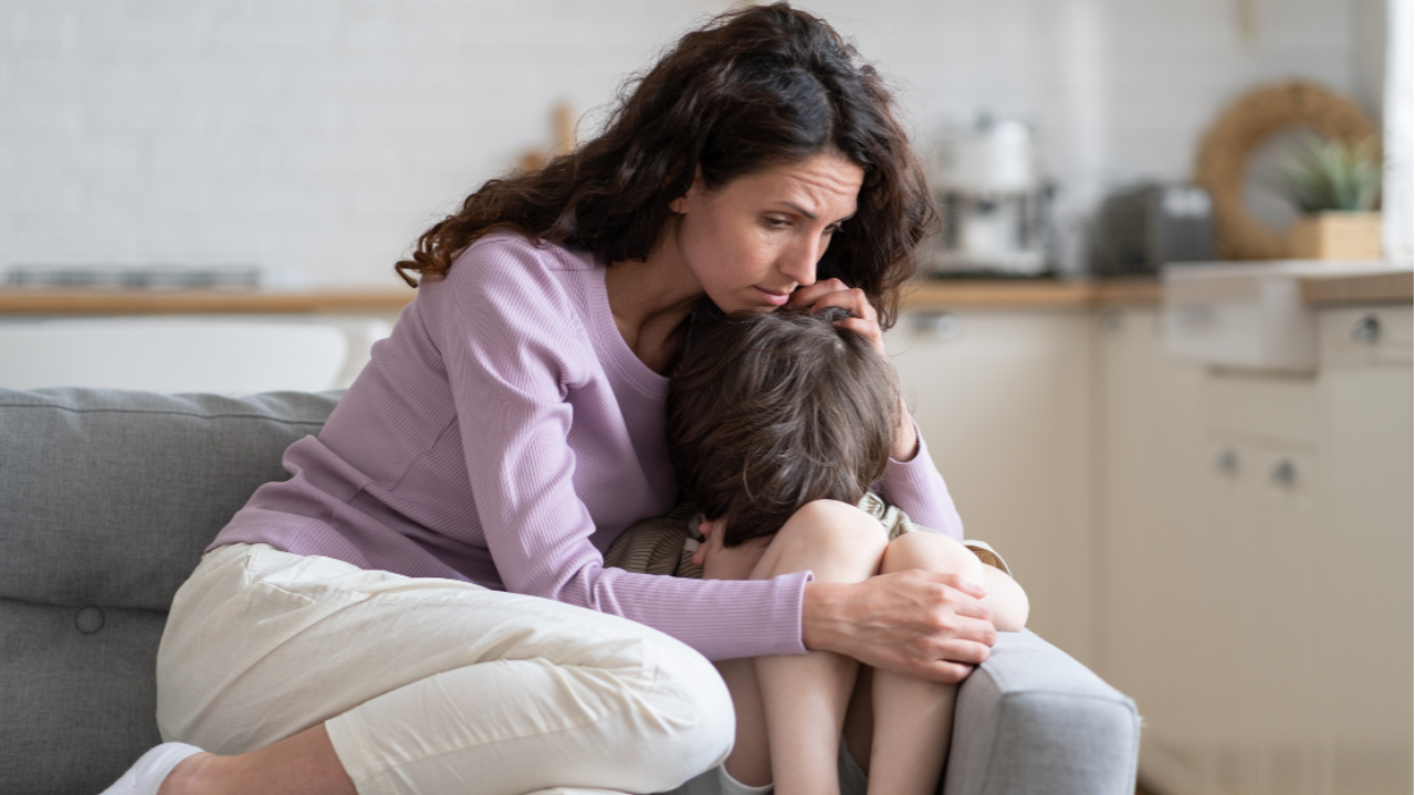 Mother comforting her son on the sofa