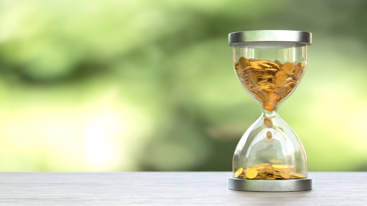 Hourglass filled with coins - showing time and consistency building wealth
