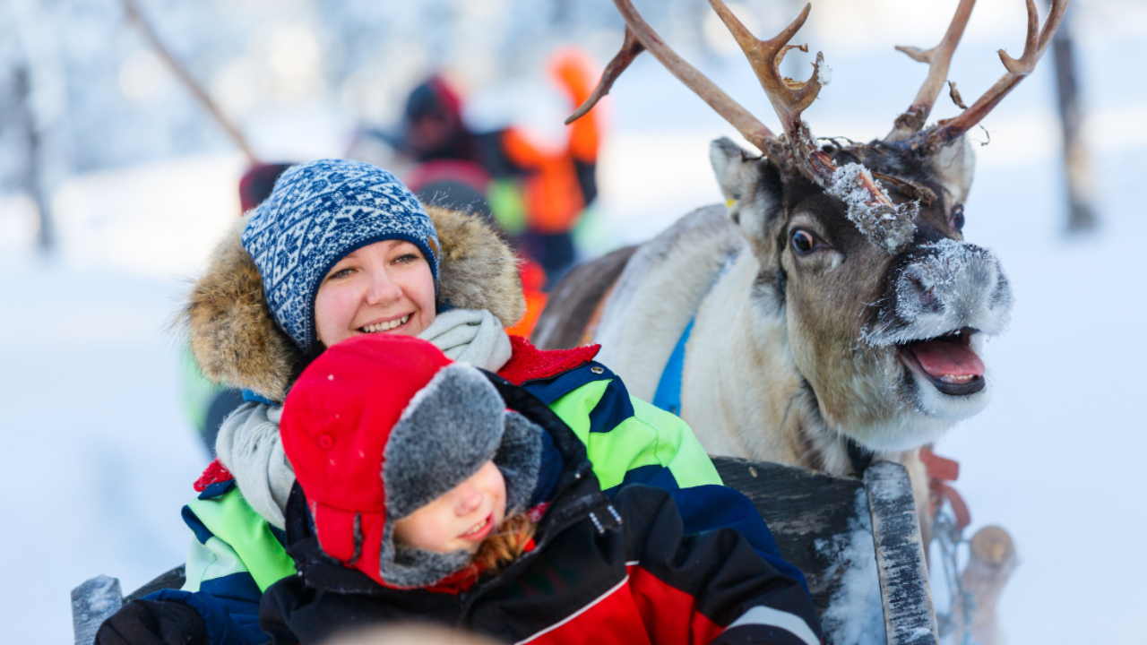 Mother and son enjoying a reindeer ride in snowy Lapland
