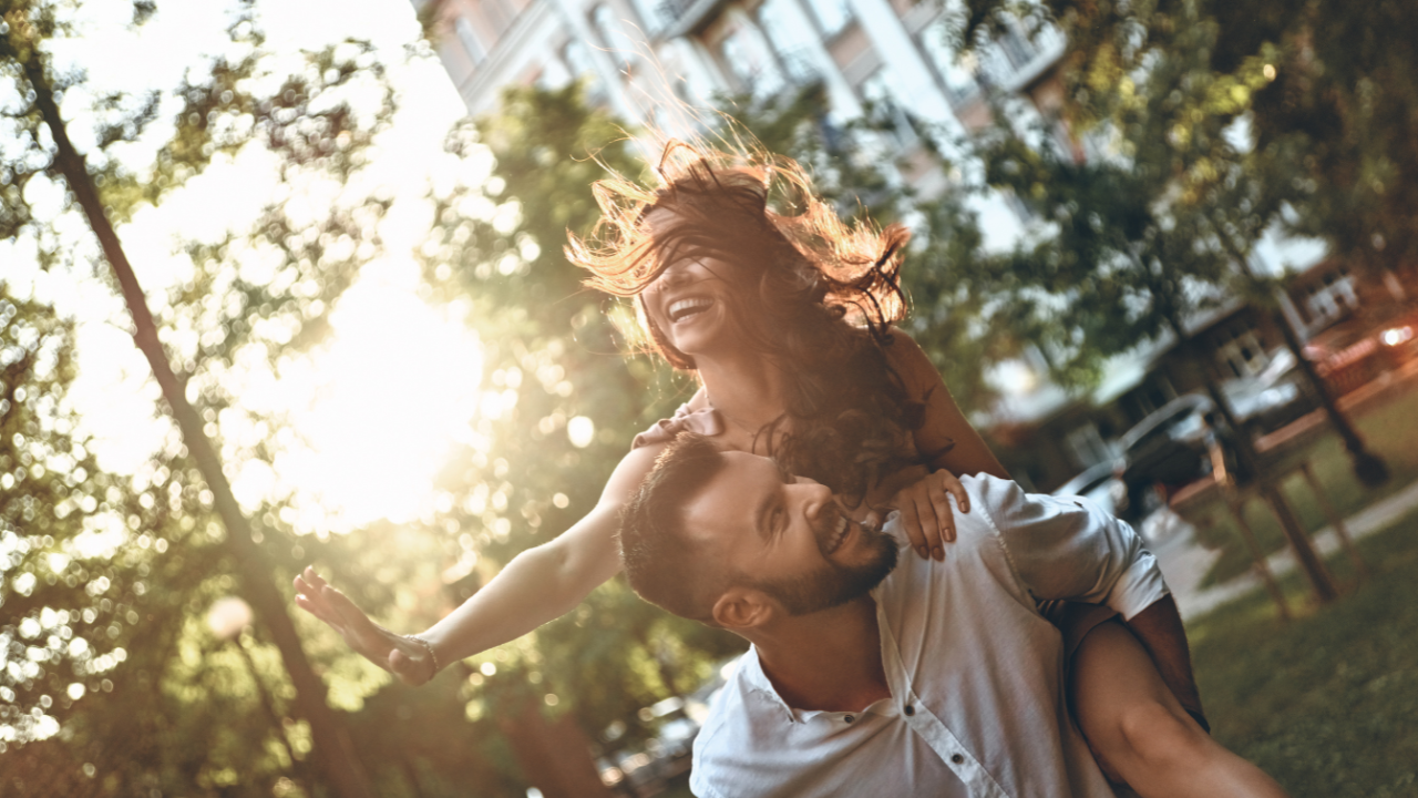 A heterosexual couple where the woman is riding piggy back on the man. They are very playful in expression and body language. 