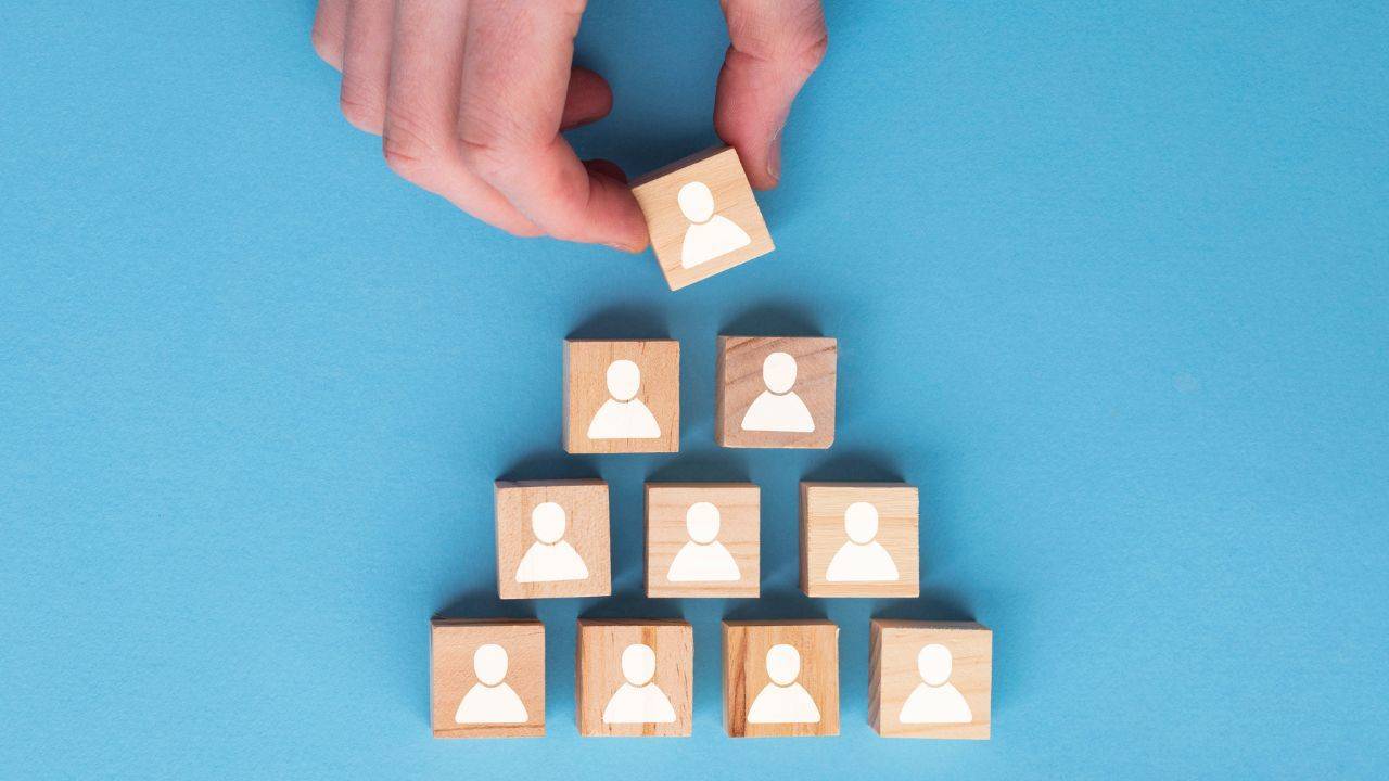 Pyramid of blocks with human silhouettes to represent members - hand adding one on top