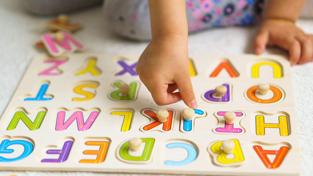 elementary aged child completing wooden puzzle of alphabet letter
