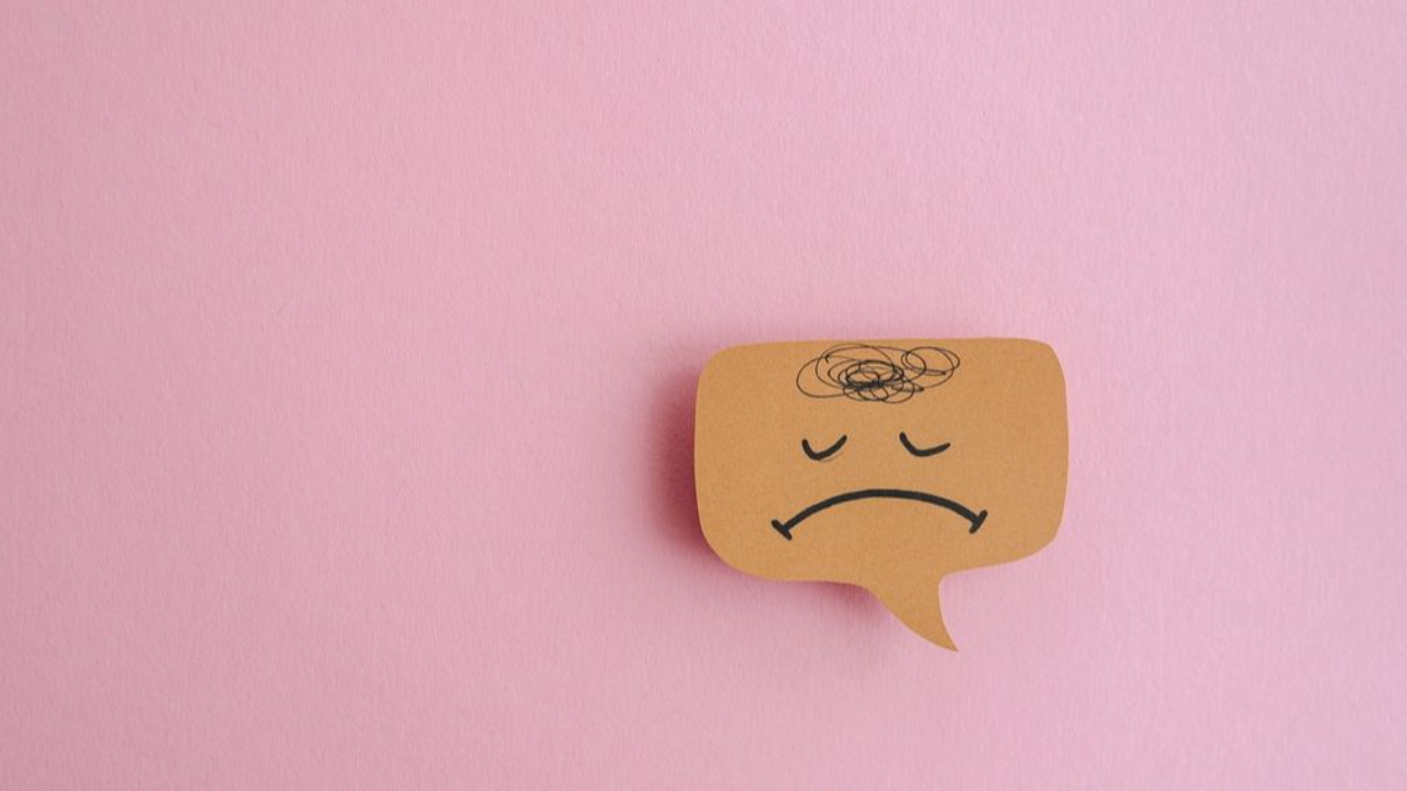 Close-up of sad face against pink wall.