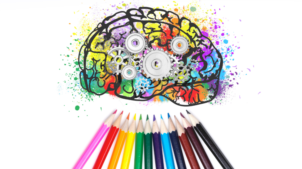 The drawing of a brain with several coloring pencils underneath.