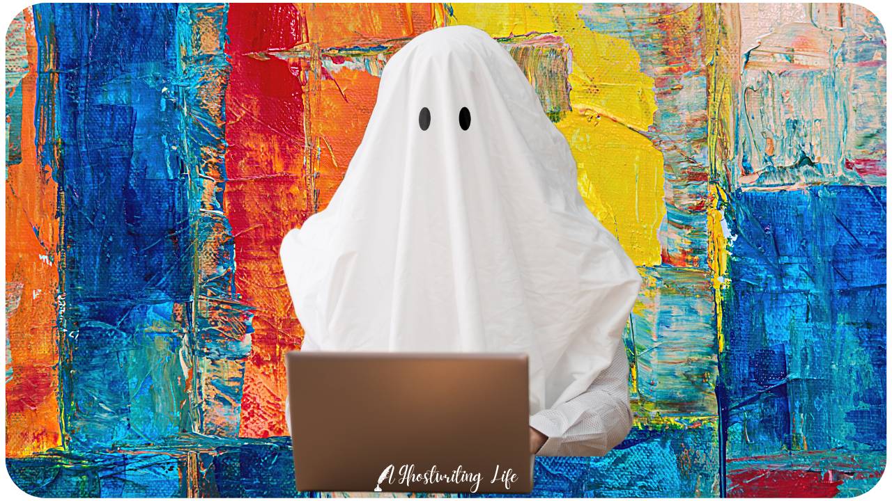 A human ghost in a sheet ghost costume typing on a laptop in front of a colorfully painted wall.