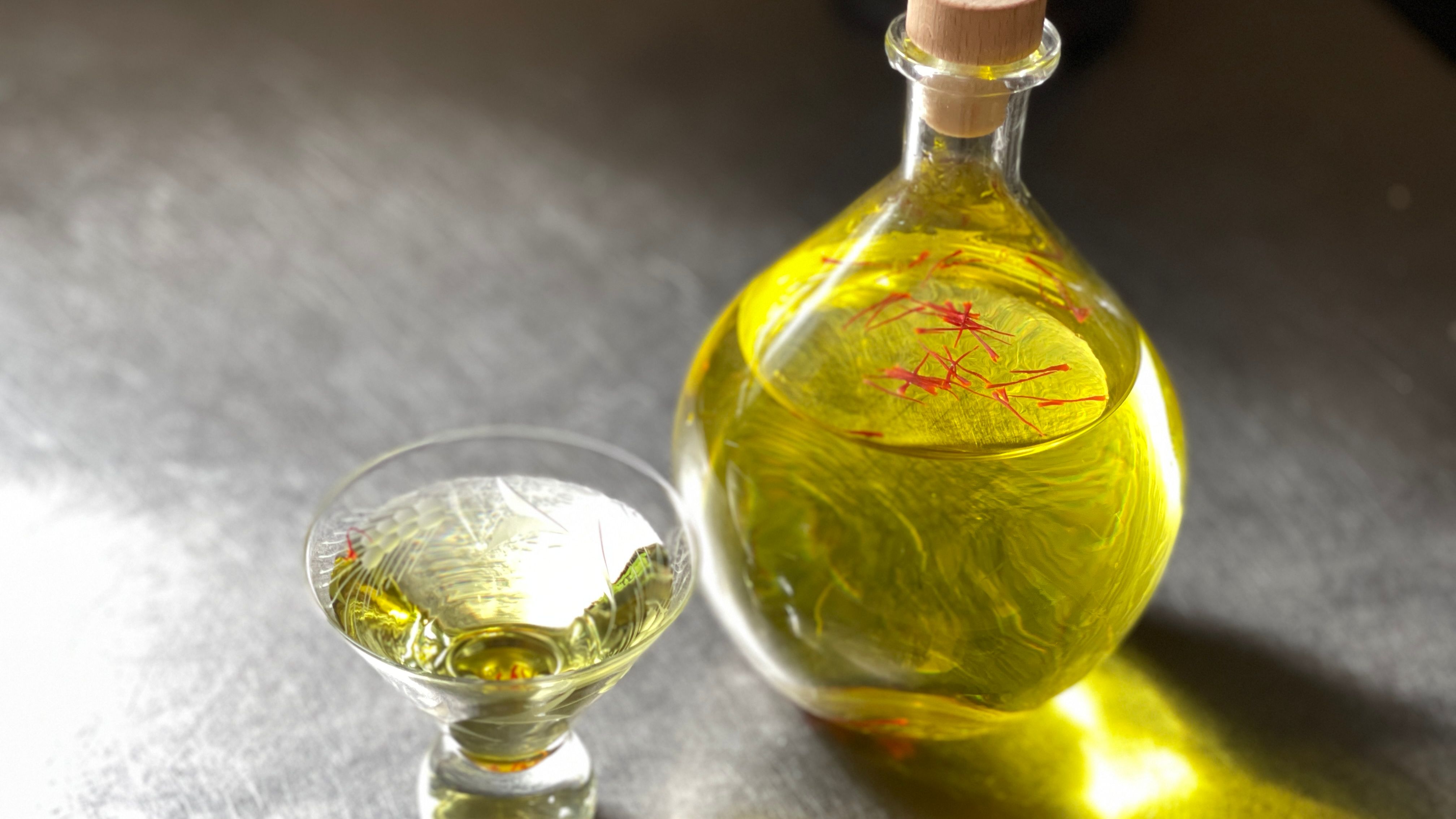 saffron water in a glass decanter with a small glass full next to it.