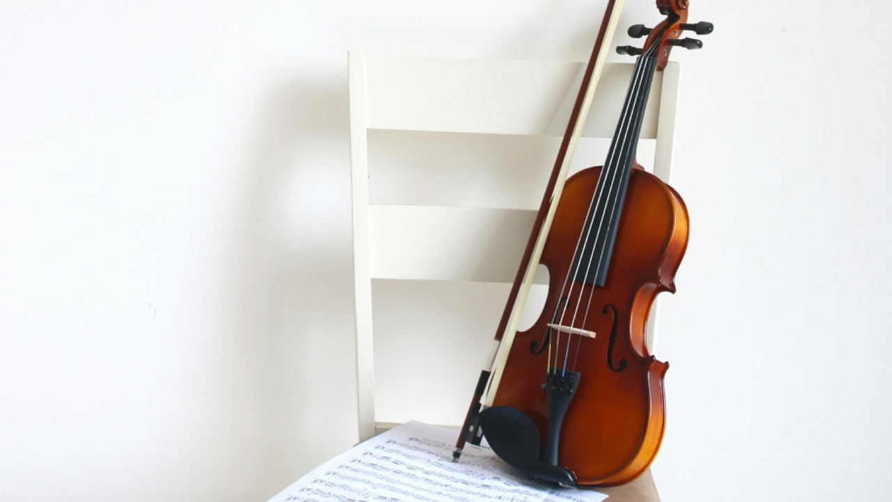 rich brown violin on a white chair against a white wall