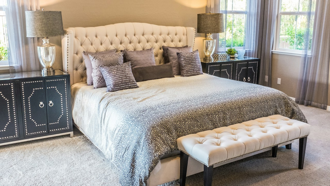 Bright serene master bedroom with made bed sheer curtains and soft natural daylight