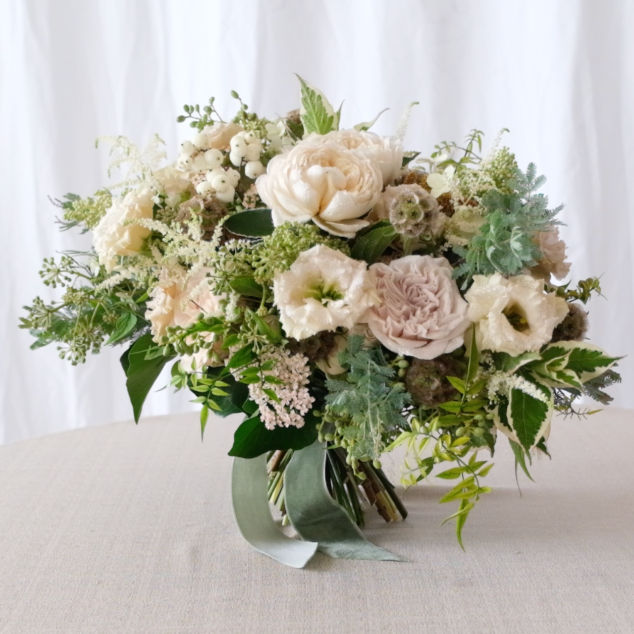 The Garden Bridal Bouquet by Joseph Massie taken from The Wedding Masterclass. Garden style bridal bouquet with soft ivory roses, lisianthus and seasonal foliage in a natural, hand tied design
