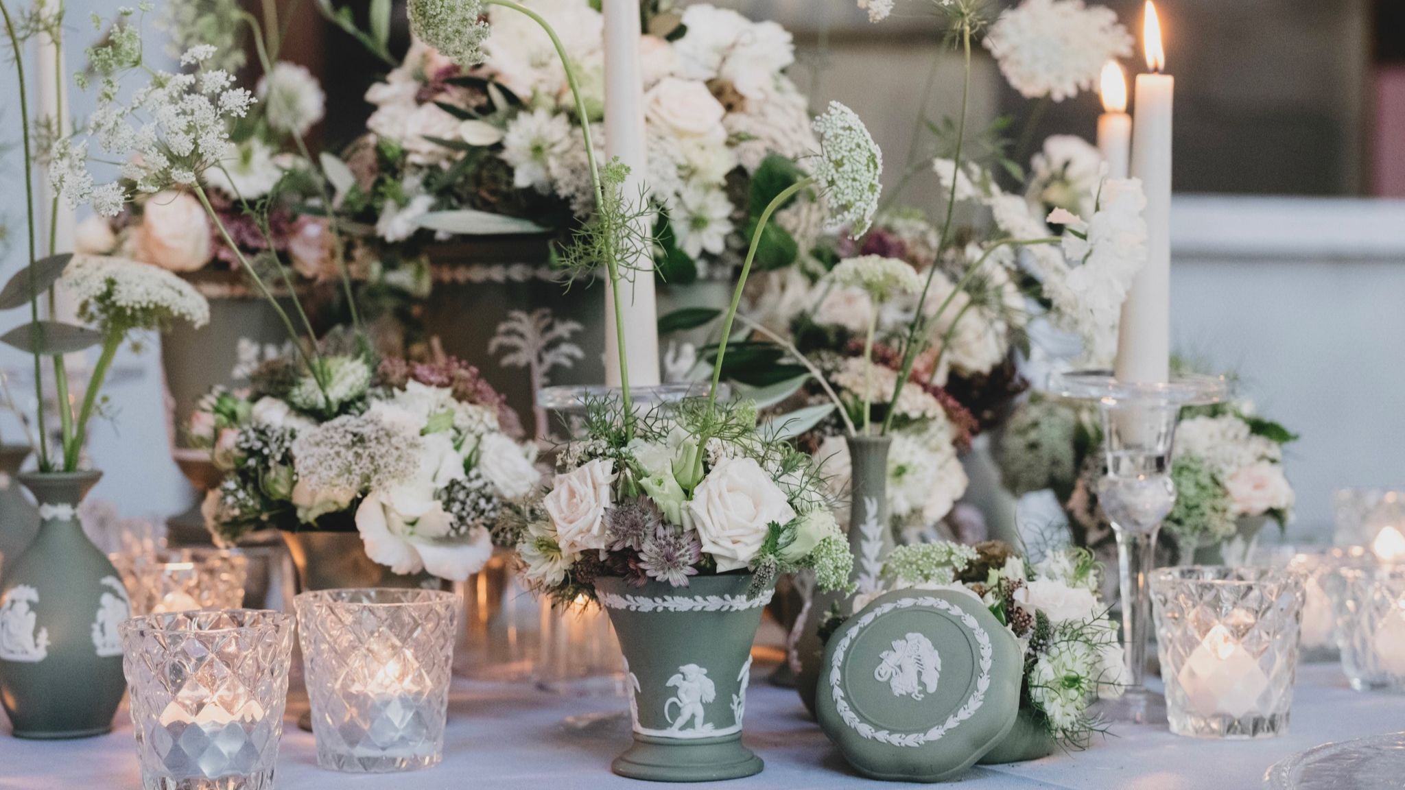 Wedding floral centrepiece design with pastel roses, textured foliage, and candlelit table styling for reception décor