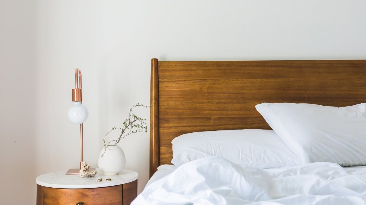 unmade bed with lamp on a wooden side table