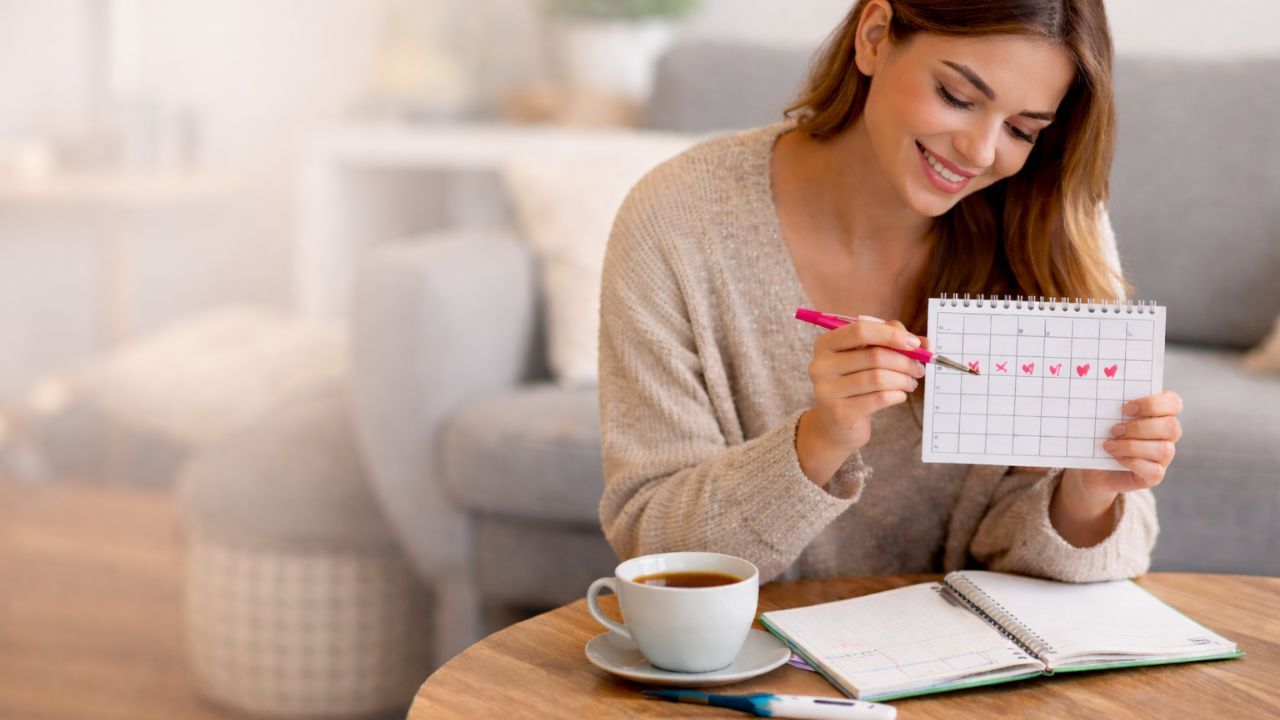 Woman tracking menstrual cycle on calendar to monitor fertility signs