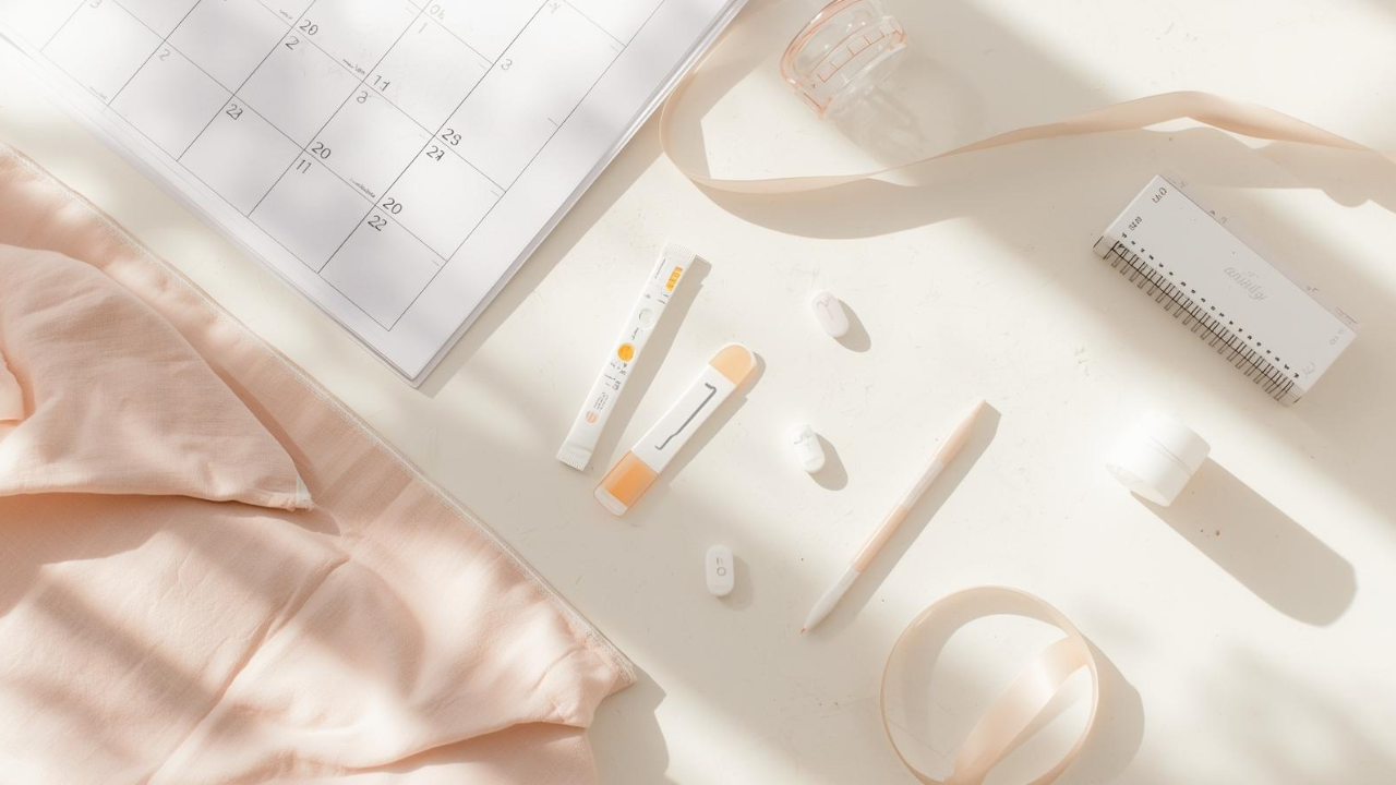 Fertility tools flatlay with ovulation tracker, cycle calendar, and wellness accessories.