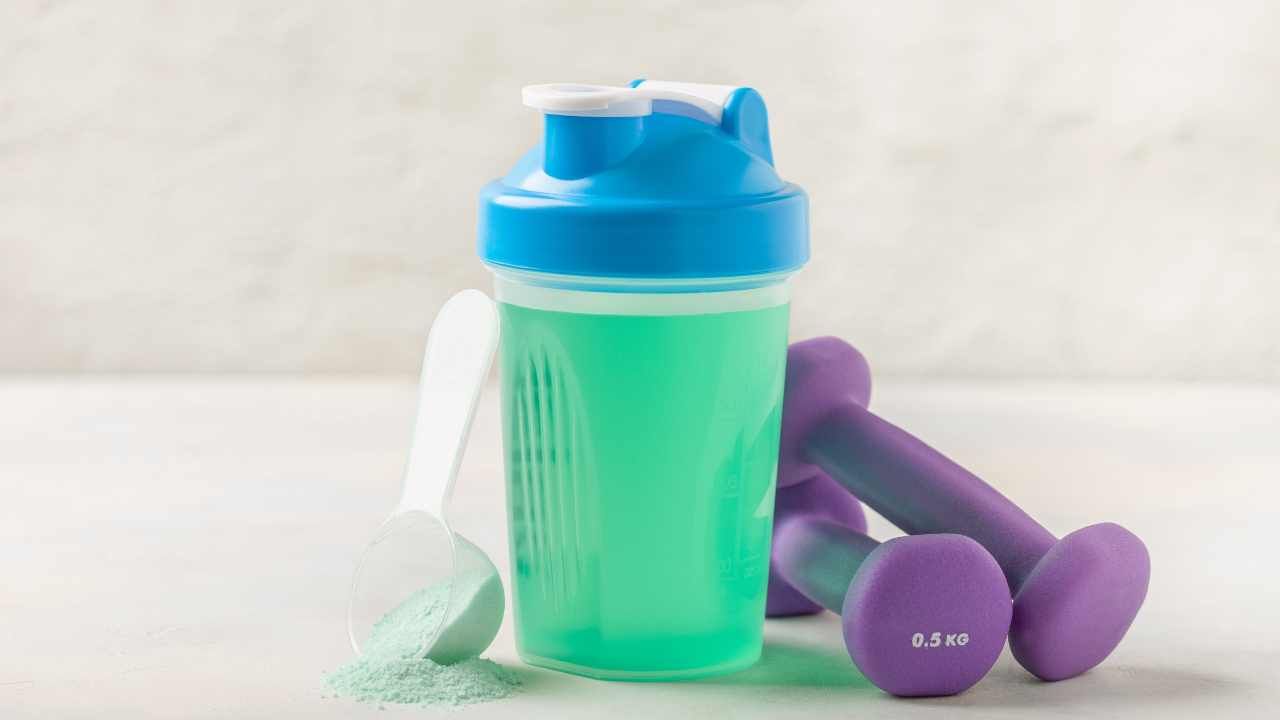 an electrolyte product in a shaker with some dumbbells near it