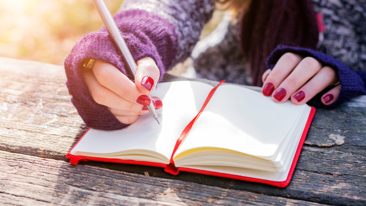 manicured hands writing in a journal