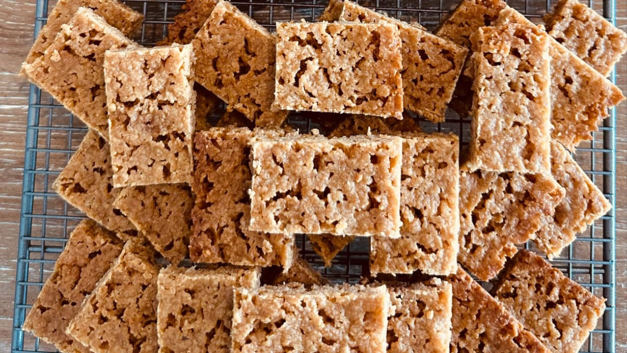 Homemade grain-free Primalanzac Slice made with coconut, almond meal, and maple syrup, freshly baked and cooling on a tray – a wholesome flapjack alternative.