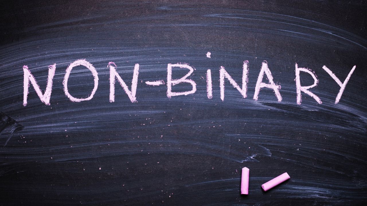 Image is of a chalkboard with pink chalk and the word non-binary written in pink chalk, for a post with three ways to be a better ally to the non-binary community. 