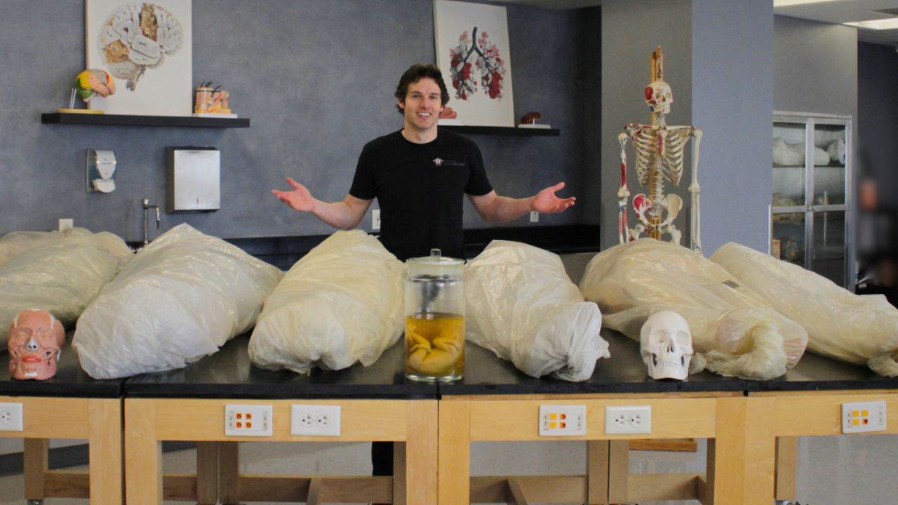 Co-founder and anatomist Jonathan Bennion standing behind wrapped human cadaver specimens inside the Institute of Human Anatomy lab.