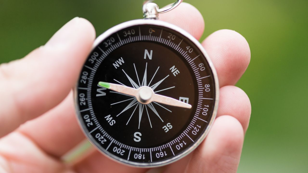 Close up image of fingers holding a compass.