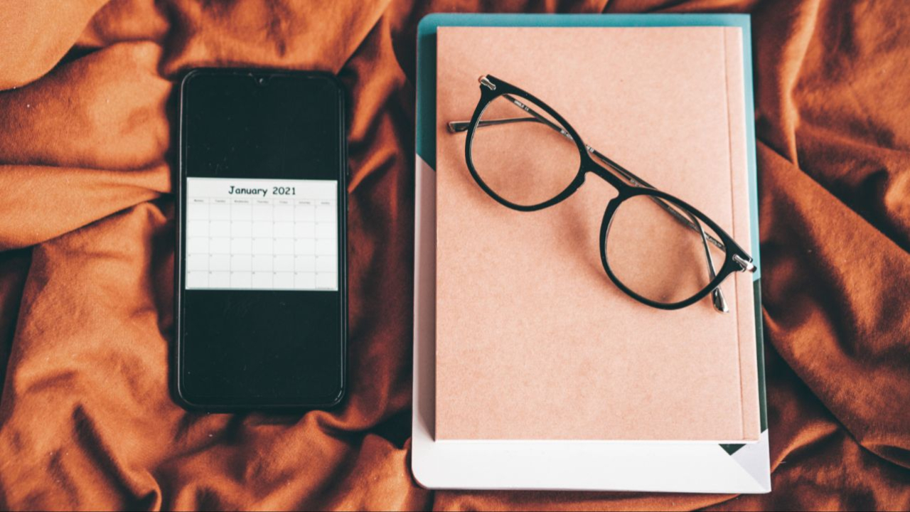 Tablet, phone, and eyeglasses sitting on a scrunched up blanket.