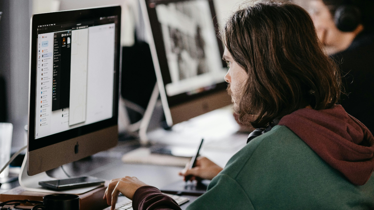 Image of creative designer working on tablet with stylist pen and designing a graphic on a computer.