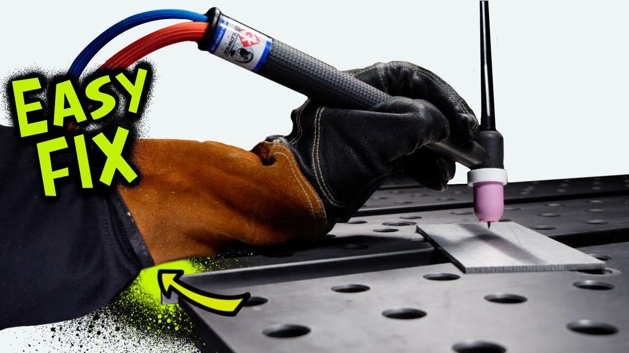 TIG welder in black gloves demonstrating close torch positioning on an aluminum workpiece on a metal welding table, with text overlay reading "Easy Fix"