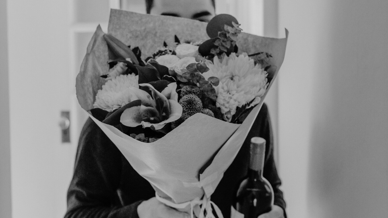 Man bringing flowers and wine, taking intentional romantic action to keep the connection from slipping into just friendship.
