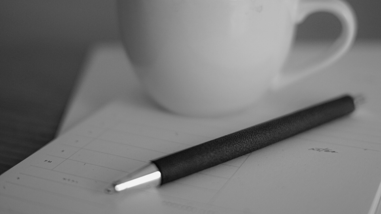 A pen on a notebook beside a mug, symbolizing traditional therapeutic reflection and why it doesn’t always help men emotionally.