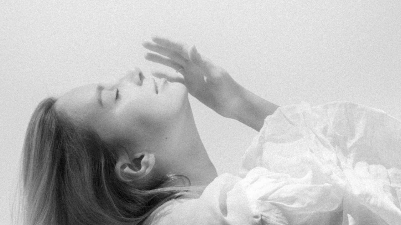 A woman in soft light with her eyes closed, symbolizing calm, healthy feminine energy that often goes unnoticed.