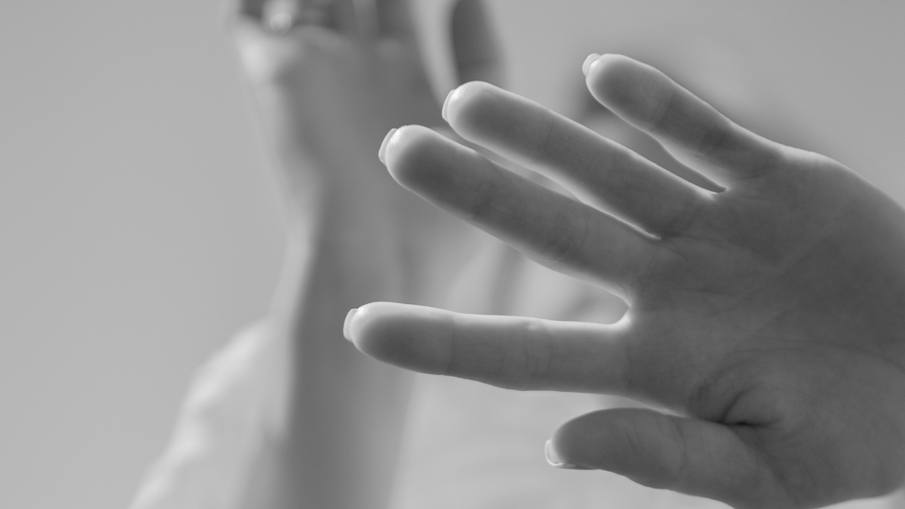 Close-up of a hand held up toward the camera, suggesting emotional distance or withdrawal.