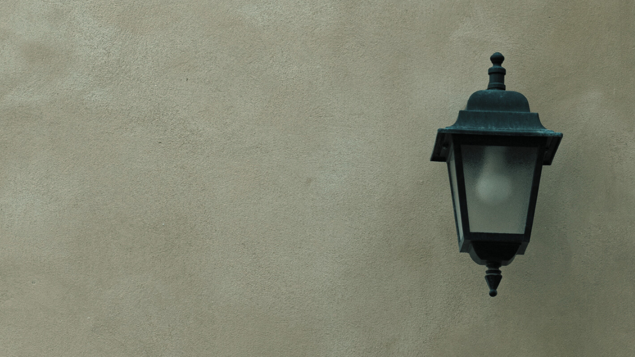 A single wall lamp on an empty wall, symbolizing isolation and introspection