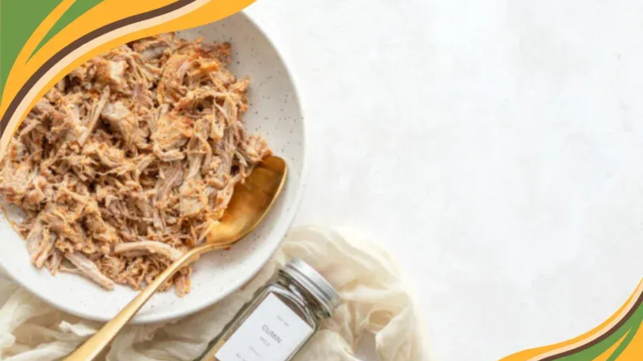 A bowl of shredded adobo pulled pork sits on the left side of the image with a gold spoon resting inside. A small jar of cumin and a light cloth sit beside the bowl. The right side of the image has open white space. The warm green and gold border accents match the GRWL brand style.
