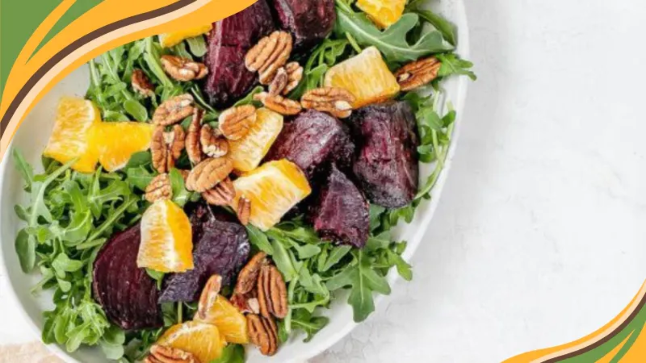 Fresh arugula salad with roasted beets, orange slices, and crunchy pecans in a white bowl.
