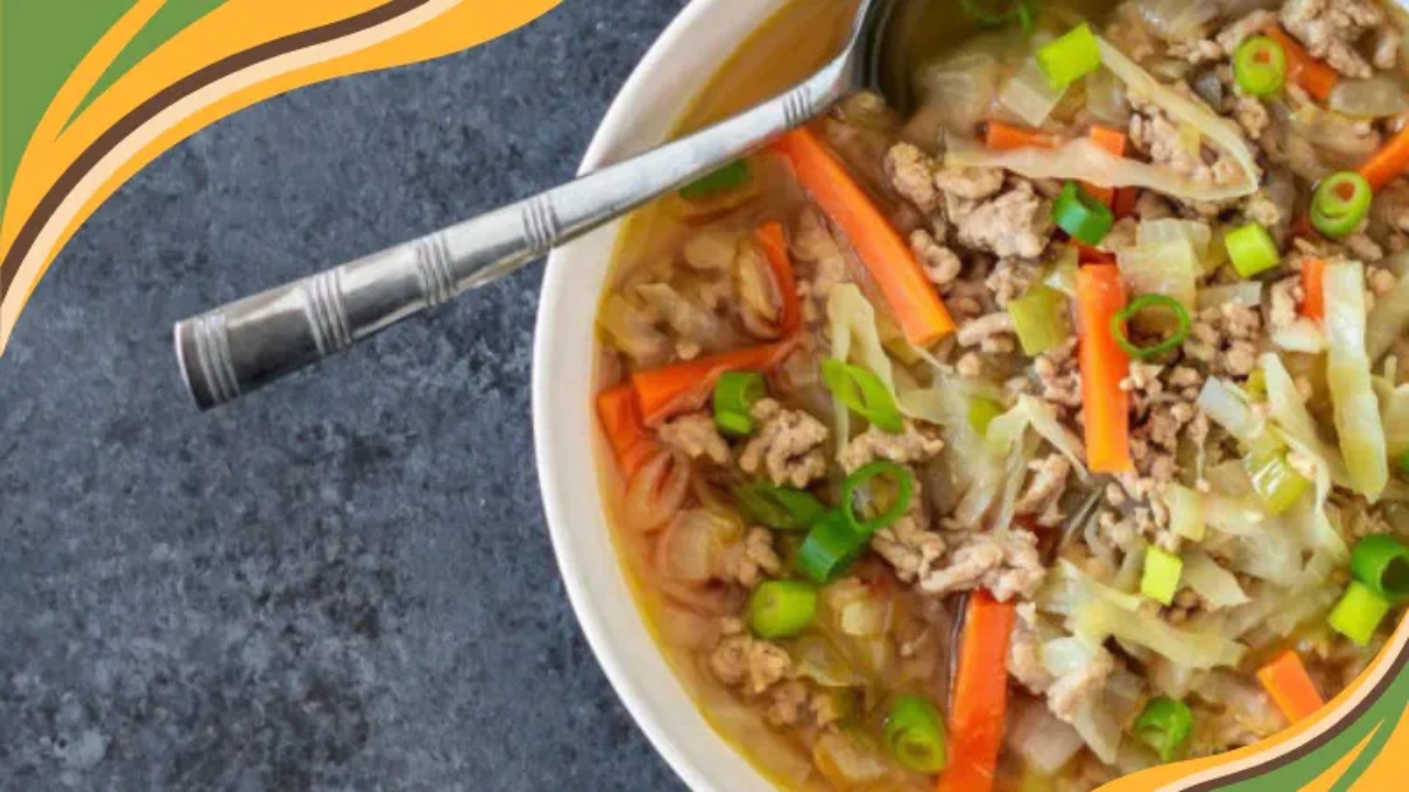 Hearty bowl of egg roll soup with ground meat, cabbage, carrots, and green onions in a savory broth.