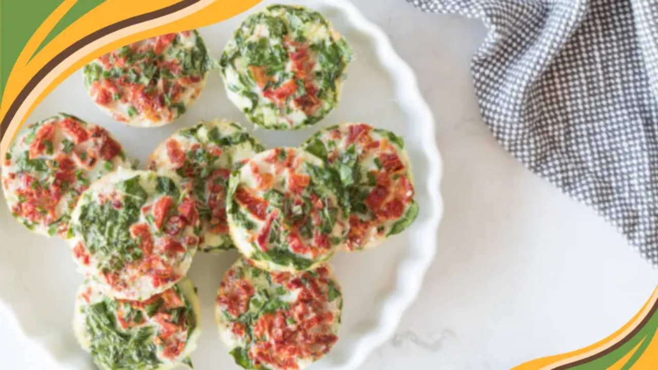 Mini egg muffin cups with spinach and diced tomatoes served on a white plate, perfect for a healthy breakfast.