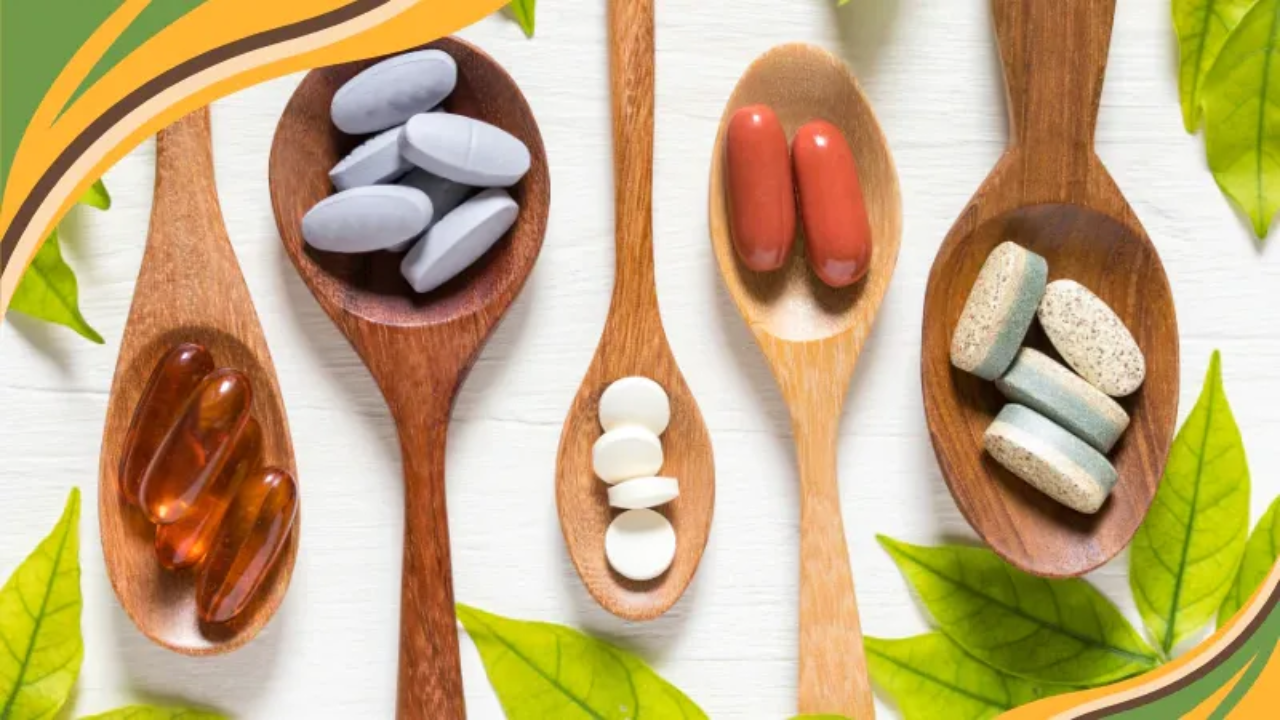Wooden spoons arranged on a light surface, each holding different vitamins and supplements including capsules, tablets, and softgels. Green leaves and warm accent graphics frame the image, suggesting a natural approach to supplements and thoughtful wellness choices.