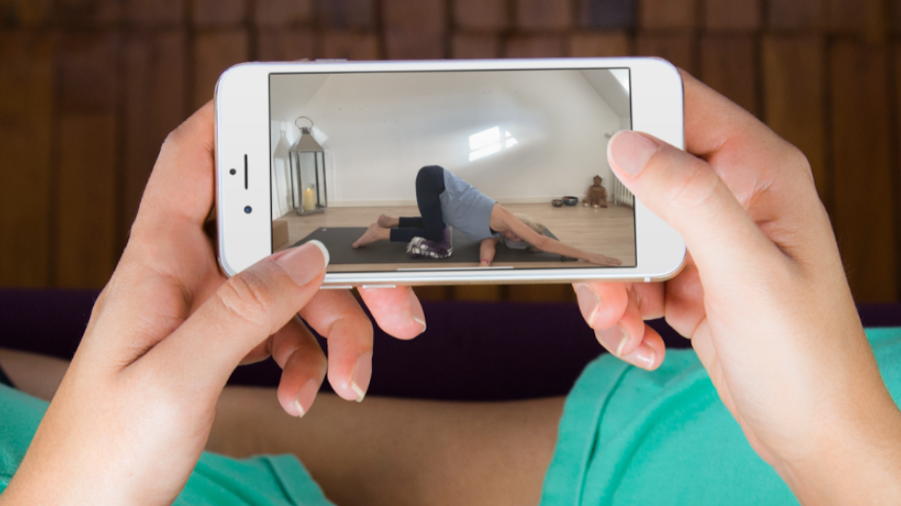 Woman holding mobile phone showing Julie Ann Garrido teaching online yoga classes for menopause 