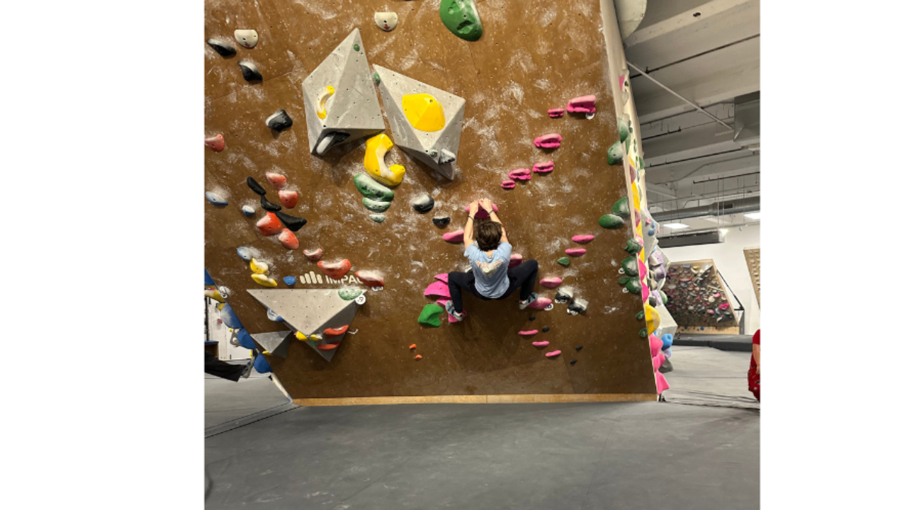 Teen climbing an indoor rock wall during a quiet moment of embodied healing