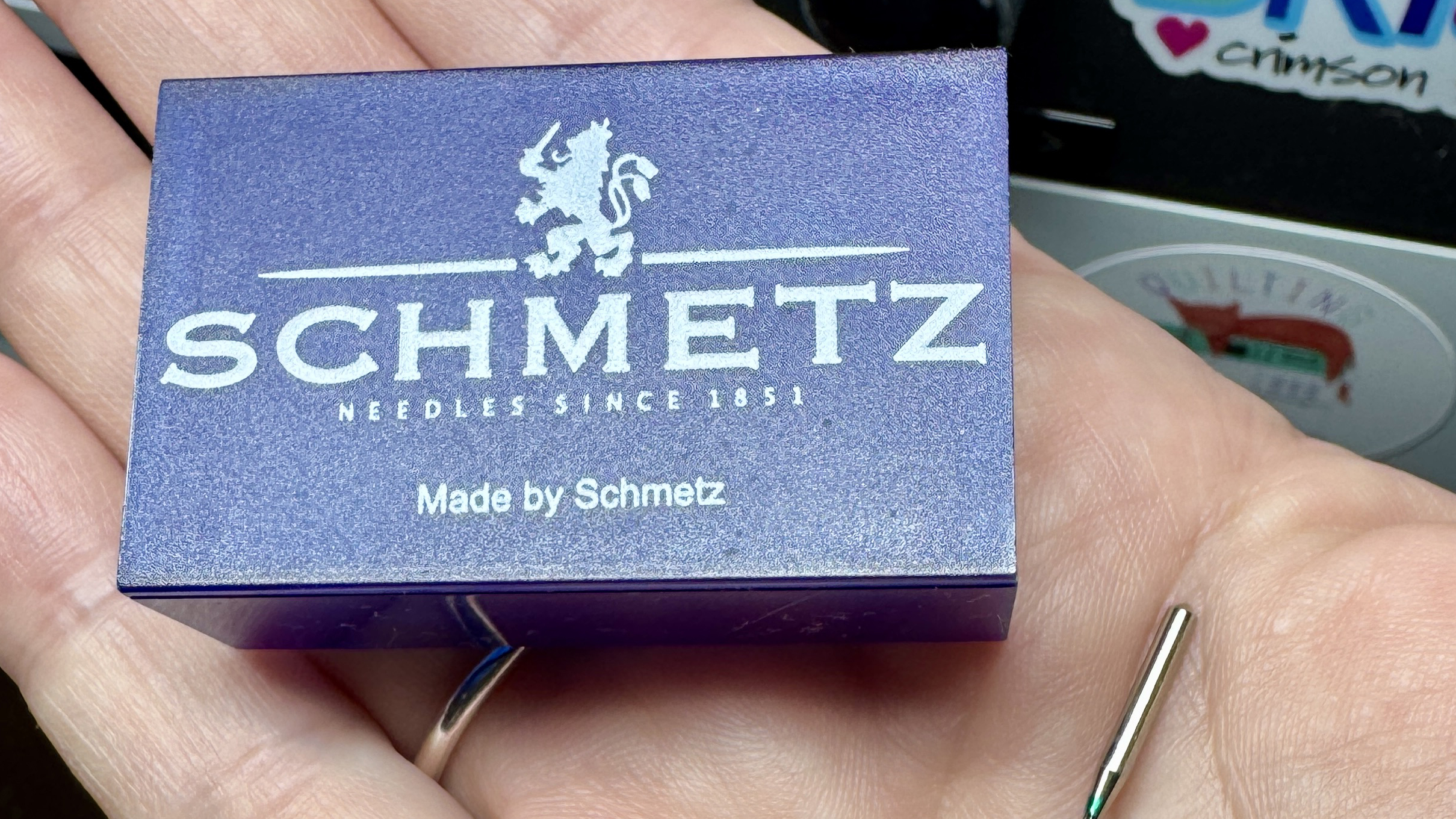hand holding a case of sewing machine needles